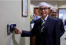  ?? – Bernama photo ?? Mohd Shukri scans his thumb to clock-in on his first day as menteri besar yesterday.