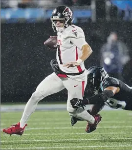  ?? Rusty Jones Associated Press ?? FALCONS QUARTERBAC­K Marcus Mariota runs from linebacker Frankie Luvu in the rain. Mariota was sacked five times, including twice on a late drive.