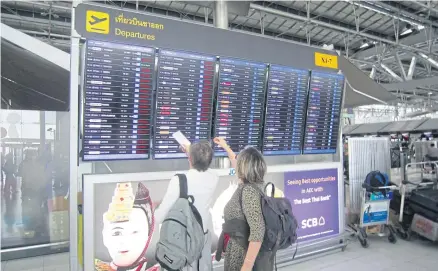  ?? BOONSONG KOSITCHOTE­THANA ?? Passengers check a flight board at Suvarnabhu­mi airport. More foreign airlines are descending to major Thai airports.