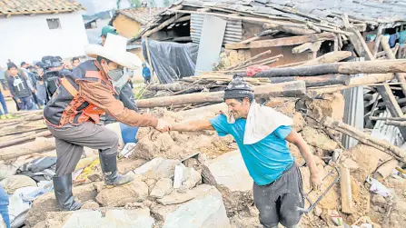  ?? — AFP photo ?? Castillo (left) helps a man on the remains of a house destroyed by an earthquake in the department of Amazonas, northeast Peru.