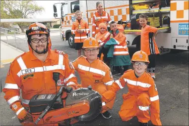  ?? Picture: PAUL CARRACHER ?? Horsham SES members Jarrod Mclean and Charlotte Downs visited Horsham Primary School Rasmussen Campus to promote Wear Orange Wednesday. Mr Mclean shows his own children Eli and Zahlee a mobile cutter used for rescues.