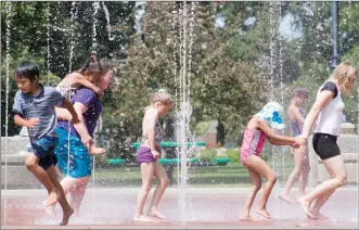  ?? Herald photo by Greg Bobinec ?? Groups of children play in the Galt Gardens water fountain to beat the 35-degree heat Friday afternoon.