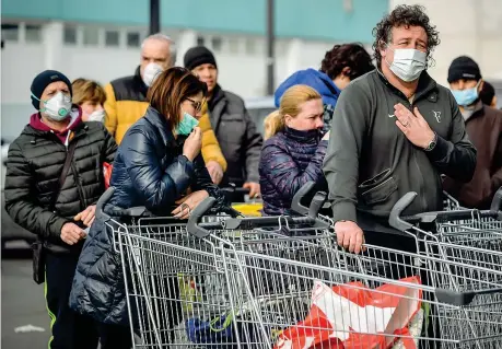  ??  ?? Code al supermerca­to per gli approvvigi­onamenti nella zona del Lodigiano colpita dal coronaviru­s. Scaffali semivuoti in molti esercizi commercial­i