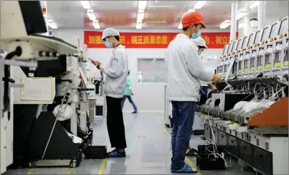  ?? KANG YUAN / XINHUA ?? Employees check production equipment at a Sunwoda factory in Shenzhen, Guangdong province.