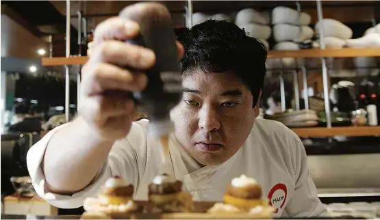  ?? Cris Bouroncle/AFP ?? O chef Mitsuharu Tsumura finaliza prato no Maido, eleito pela primeira vez o melhor restaurant­e da América Latina; no alto, seu salão principal