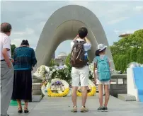  ?? — AFP ?? A woman prays for the world’s first atomic bombing victims while a man with a girl takes photos at the Peace Memorial Park in Hiroshima,