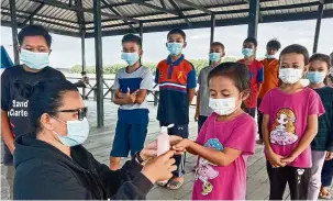  ??  ?? At Pulau Mumiang, Hartina teaches children the importance of physical distancing and hand hygiene during the Covid-19 pandemic. (Note: This photo was taken before the conditiona­l MCO in Sabah). (Right) “The best way to find yourself is to lose yourself in the act of helping others,” says Hartina. — Photos: HARTINA BULATING ARSSID