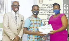  ??  ?? Student Nicoy Walters receives his tablet — one of 181 handed out recently under a joint UN project — from UNDP Programme Coordinato­r Alicia Bowen-mcculskie (right). Sharing in the moment is Member of Parliament Desmond Mckenzie.