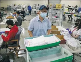  ?? Irfan Khan Los Angeles Times ?? BRANDON KIMPARK collects recall ballots inspected by election staff at the Los Angeles County registrar of voters’ satellite office at the Pomona Fairplex.