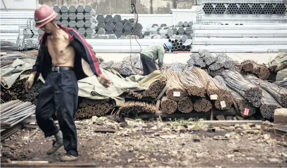  ??  ?? WORKERS prepare to lift bundles of steel rod with a crane at a stockyard on the outskirts of Shanghai in July. China made three times more steel than Europe and North America in 2017. |