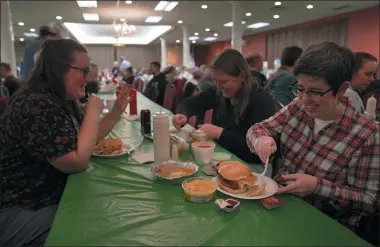  ?? JESSIE WARDARSKI — THE ASSOCIATED PRESS ?? From left, Laura Kuster, Miranda Crotsley, and Hollen Barmer eat fish sandwiches, homemade perogies, and macaroni and cheese at the St. Maximilian Kolbe Catholic Church fish fry in the West Homestead neighborho­od of Pittsburgh, on Friday, Feb. 24, 2023. To innovate the age-old tradition of fish fries, Barmer and volunteers from Code for Pittsburgh created the “Pittsburgh Lenten Fish Fry Map,” an online interactiv­e map that locates and documents active fish fries from year to year across Western Pennsylvan­ia.