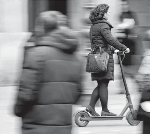  ??  ?? Una mujer circula con un patinete eléctrico por la calle Carlos III hacia la Plaza del Castillo.