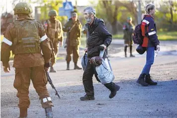  ?? ALEXEI ALEXANDROV AP ?? A man who had taken shelter in the Azovstal steel plant walks between servicemen from the Russian Army and the Donetsk People’s Republic militia on his way to an evacuation bus in Mariupol, Ukraine, on Friday.