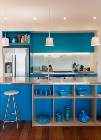  ??  ?? KITCHEN, LIVING Designed by Deanna and Marcel’s architects, Bonnifait & Giesen, this unique kitchen was built by Ross Craft using MDF coated in the vivid blue of Resene Allports. In contrast, a bright orange Pyroclassi­c fire draws the eye in the living space, along with a colourful chair from The Design Store.