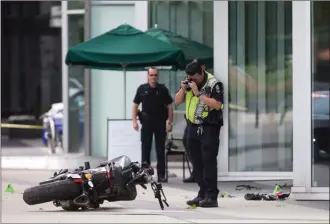  ?? The Canadian Press ?? A police officer photograph­s a motorcycle after a female stunt driver working on the movie Deadpool 2 died after a crash on set in Vancouver on Monday.