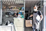  ??  ?? Fish-and-chip Friday is back as people collect their meals at The Vintage Fish in Wimbledon, south-west London, as stores start to open in the aftermath of the first phase of the coronaviru­s lockdown