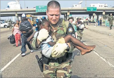  ??  ?? A soldier rescues a girl stranded on the highway in Louisiana as New Orleans residents flee Hurricane Katrina on September 3, 2005