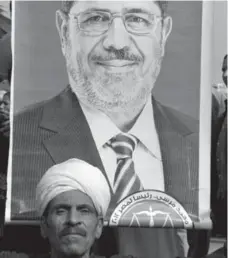  ?? THOMAS HARTWELL/THE ASSOCIATED PRESS ?? A supporter holds a poster of Egyptian President Mohammed Morsi near Cairo University Saturday, at one of many rallies organized by the Muslim Brotherhoo­d to counteract large opposition protests held this past week.