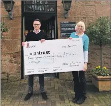  ?? ?? Kevin Meechan presents the first cheque to Sheila Gilmore of the Arran Trust outside the Home Farm shop.