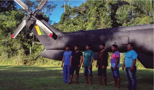  ??  ?? Indigenous Ye’kuana pose in front of a helicopter at the 5th Special Frontier Platoon in Auari, Roraima state, Brazil, amid the coronaviru­s pandemic.