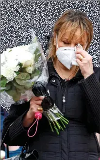  ??  ?? EMOTIONAL: A woman sheds a tear as she waits in line