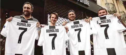  ??  ?? PEMINAT Juventus memberi sokongan kepada Ronaldo dengan mempamerka­n jersi nombor 7 di Turin, kelmarin.