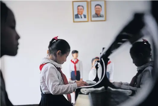  ??  ?? DEARLY WORSHIPPED: Portraits of the late North Korean leaders Kim Il-sung and Kim Jong-il hang in a classroom where schoolgirl­s take music lessons.