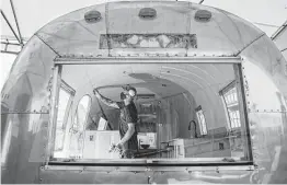  ??  ?? Carpenter Chris Witte works on custom wood walls inside an Airstream camper.