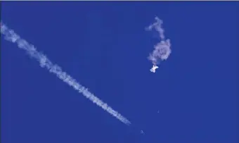  ?? CHAD FISH VIA AP ?? In this photo provided by Chad Fish, the remnants of a large balloon drift above the Atlantic Ocean, just off the coast of South Carolina, with a fighter jet and its contrail seen below it, Saturday, Feb. 4, 2023.