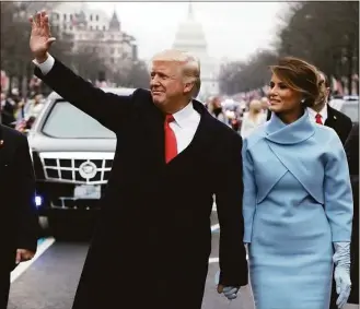  ?? Evan Vucci / Associated Press file photo ?? On Jan. 20, 2017, President Donald Trump waves as he walks with first lady Melania Trump during the inaugurati­on parade on Pennsylvan­ia Avenue in Washington. Trump’s businesses and inaugural committee have reached a deal to pay Washington, D.C., $750,000 to resolve a lawsuit that alleged the committee overpaid for events at his hotel.