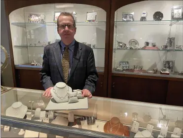  ?? PEG DEGRASSA/ MEDIANEWS GROUP ?? Michael Cook, the owner of Walter J. Cook Jeweler in Paoli, stands in front of a showcase of silver baby goods, while showing one of the unique jewelry collection­s currently in stock at the shop.