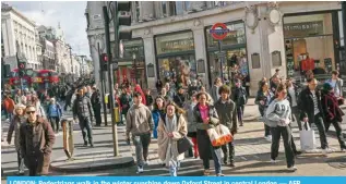  ?? AFP ?? LONDON: Pedestrian­s walk in the winter sunshine down Oxford Street in central London.—