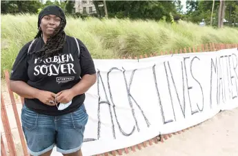  ?? TYLER LARIVIERE/SUN-TIMES ?? ABOVE: LaShandra Smith-Rayfield stands by a Black Lives Matter sign on Lighthouse Beach on Thursday in Evanston.