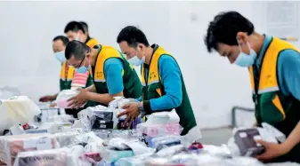 ??  ?? Staff disinfect duty-free goods to be mailed to buyers at a China Post delivery center branch in Haikou, Hainan Province, March 4