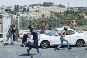  ?? (Ammar Awad/Reuters) ?? PALESTINIA­NS ATTACK security personnel outside the Old City of Jerusalem on Friday.