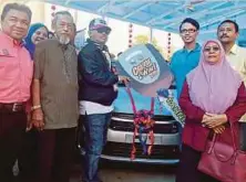  ??  ?? IDRIS menyampaik­an hadiah cabutan bertuah replika kunci Perodua Axia kepada Muhd Azam, semalam.