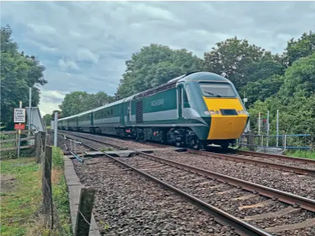  ?? BC Collection ?? Fresh out of the paintshop at Eastleigh and shortly before it started work on the 2021 Staycation Express season, No. 43058 leads five trailers and No. 43059 through Claydon Crossing, working the 5Z64 13.37 Eastleigh Arlington-Crewe HS on July 12, 2021.