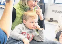  ?? ALISON JENKINS/ JOURNAL PIONEER ?? Graham Carlile leans on his grandmothe­r, Jean Carlile, as a group of moms and tots act out a storytime rhyme.