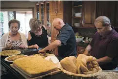  ??  ?? Don di Cocco, far right, cuts bread with his guests before a lunch at his home in Sarnia. The di Coccos are originally from Ciociaria.