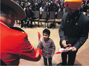  ?? KEVIN KING / POSTMEDIA NEWS FILES ?? Jasjot Mann, 5, takes a flag from a Mountie during a citizenshi­p ceremony in Winnipeg in December 2017.