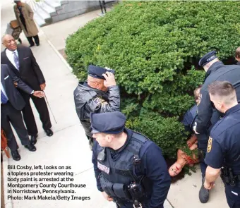  ??  ?? Bill Cosby, left, looks on as a topless protester wearing body paint is arrested at the Montgomery County Courthouse in Norristown, Pennsylvan­ia. Photo: Mark Makela/Getty Images