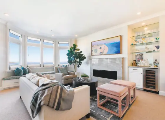  ?? Open Homes Photograph­y ?? The living room at 44 Macondray Lane, Unit 5E in Russian Hill features a bar counter with glass display shelves and a wine refrigerat­or, as well as a gas fireplace with granite surround and a sitting window with bay views.