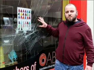  ??  ?? Liam O’Grady at the smashed window of his Mallin Street premises.