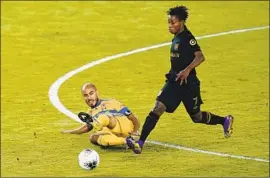  ?? John Raoux Associated Press ?? TIGRES midfielder Guido Pizarro, left, gets the ball away from LAFC forward Latif Blessing during the f irst half of a CONCACAF title game.