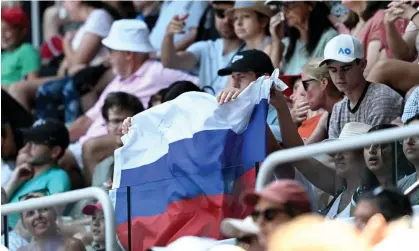  ?? Open. Photograph: Lukas Coch/EPA ?? A Russian flag is displayed by spectators during the first round match between Andrey Rublev ofRussia and Dominic Thiem of Austria at the 2023 Australian