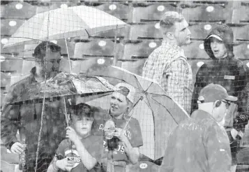  ?? TOM E. PUSKAR AP ?? Fans in Cincinnati put up their umbrellas as rain begins to fall and the Reds-Pirates game is postponed.