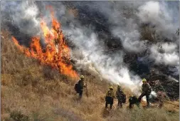  ?? Dan Watson/The Signal ?? Firefighte­rs bring a hose to knock down a Jump Fire hot spot in Saugus on Tuesday. The fire was held to 2.5 acres, Fire Department officials reported.