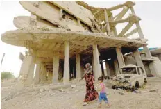  ?? — AFP ?? A Syrian woman walks past destroyed buildings in Kobane.