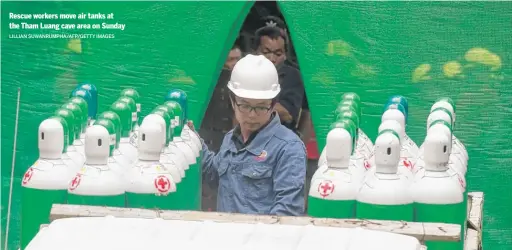  ?? LILLIAN SUWANRUMPH­A/ AFP/ GETTY IMAGES ?? Rescue workers move air tanks at the Tham Luang cave area on Sunday