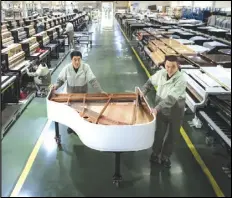  ?? XIAO YIJIU/XINHUA VIA AP ?? Workers transfer a half-assembled piano at a production factory of Parsons Music Corporatio­n in Yichang, central China’s Hubei Province, in 2021.